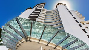 Un hotel moderno con fachada curva, varios balcones y un atrio de vidrio.