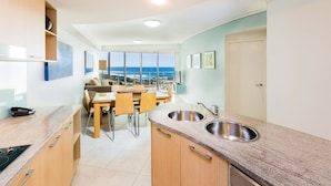 Una cocina moderna con comedor, ventanas amplias y vista al mar.
