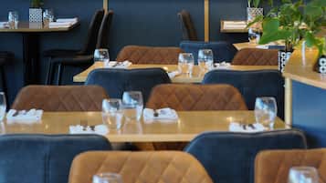 A restaurant with tables and chairs, some with menus and glasses.