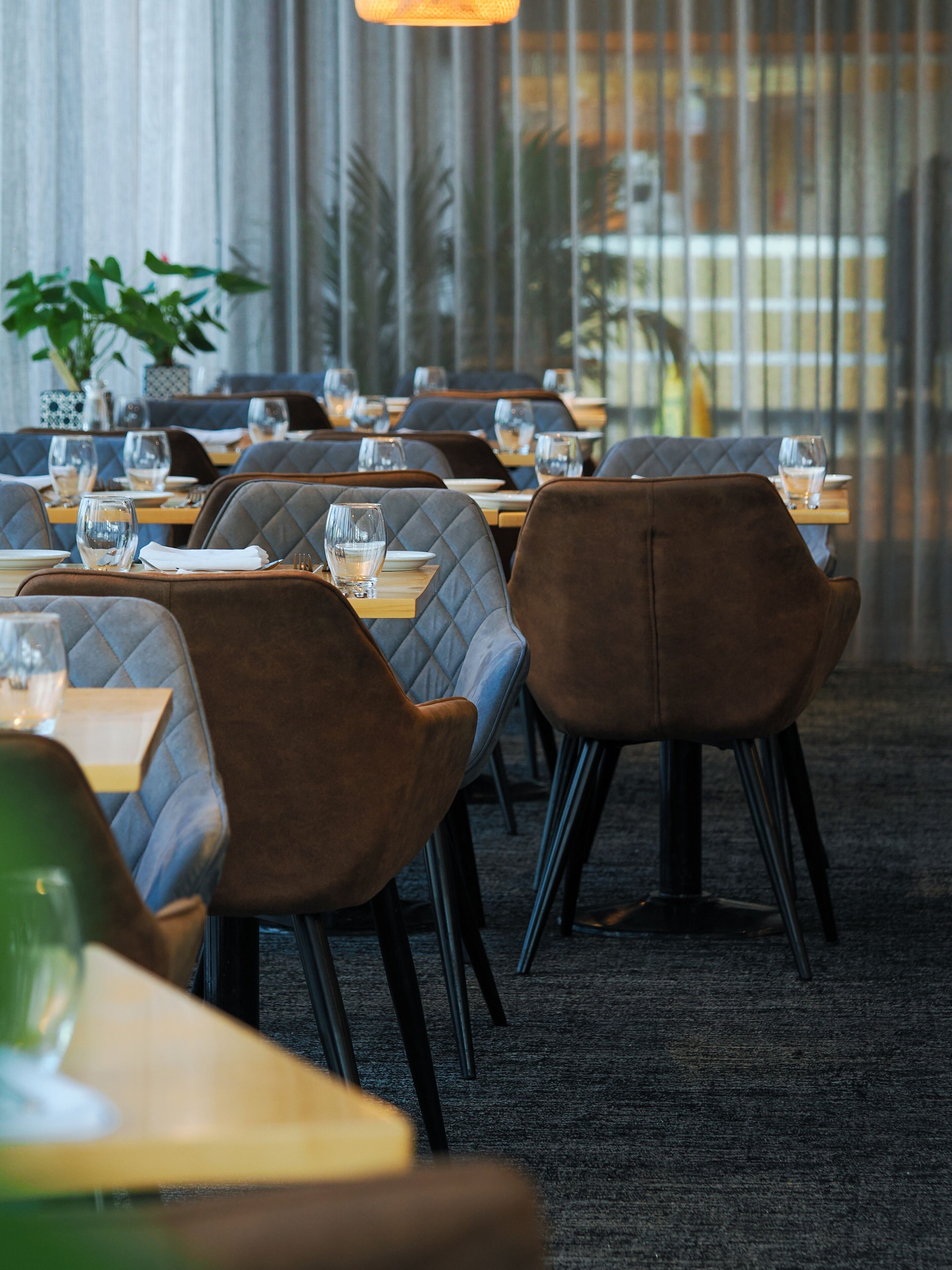 A restaurant with tables set for dining, featuring cushioned chairs and a carpeted floor.