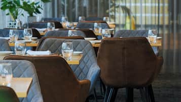 Un restaurante con mesas dispuestas para comer, con sillas acolchadas y suelo alfombrado.