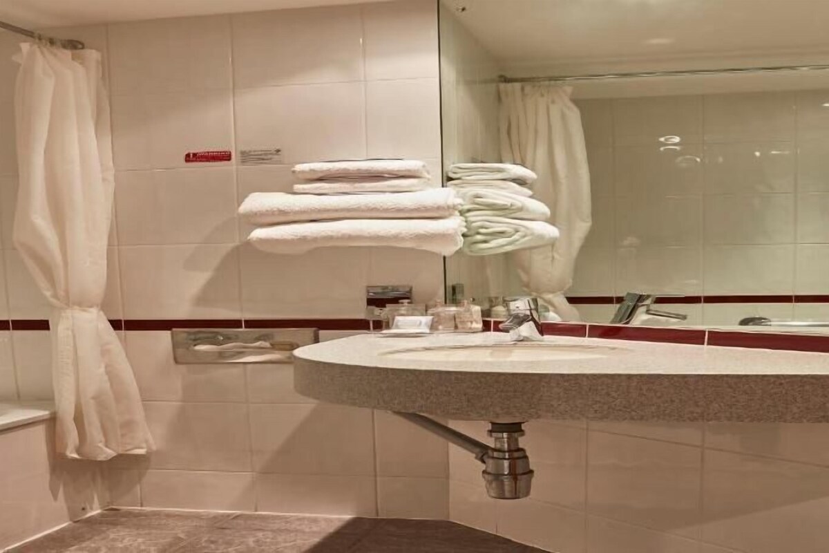 Une salle de bain avec un lavabo, un miroir et des serviettes pliées.