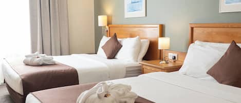 Habitación de hotel con dos camas, una mesita de noche, una lámpara y un cuadro en la pared.
