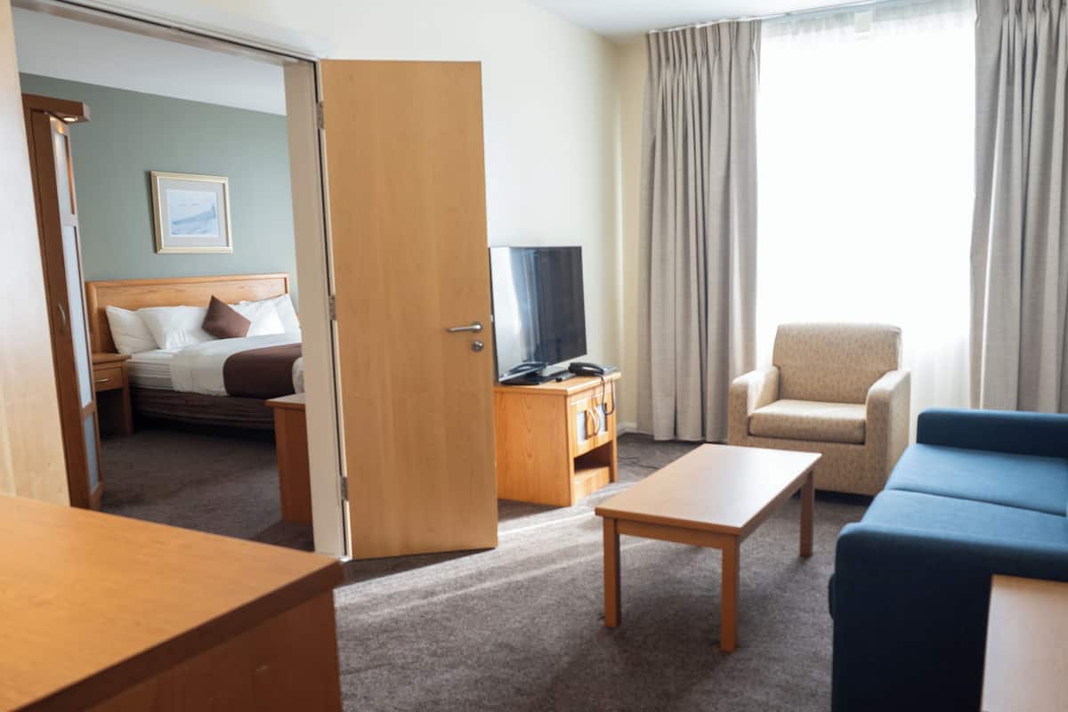 A hotel room with a bed, a TV, a desk, a chair, and a sofa.