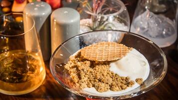 A dessert plate with a waffle and cream, surrounded by glasses and a fruit platter.