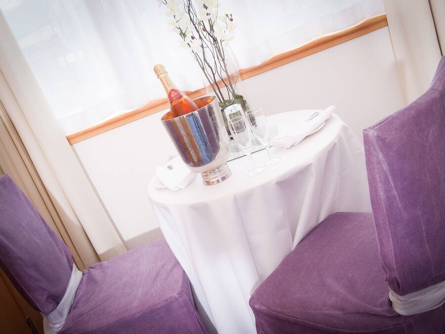 A table set with a bottle of champagne, a glass, and a vase with branches.