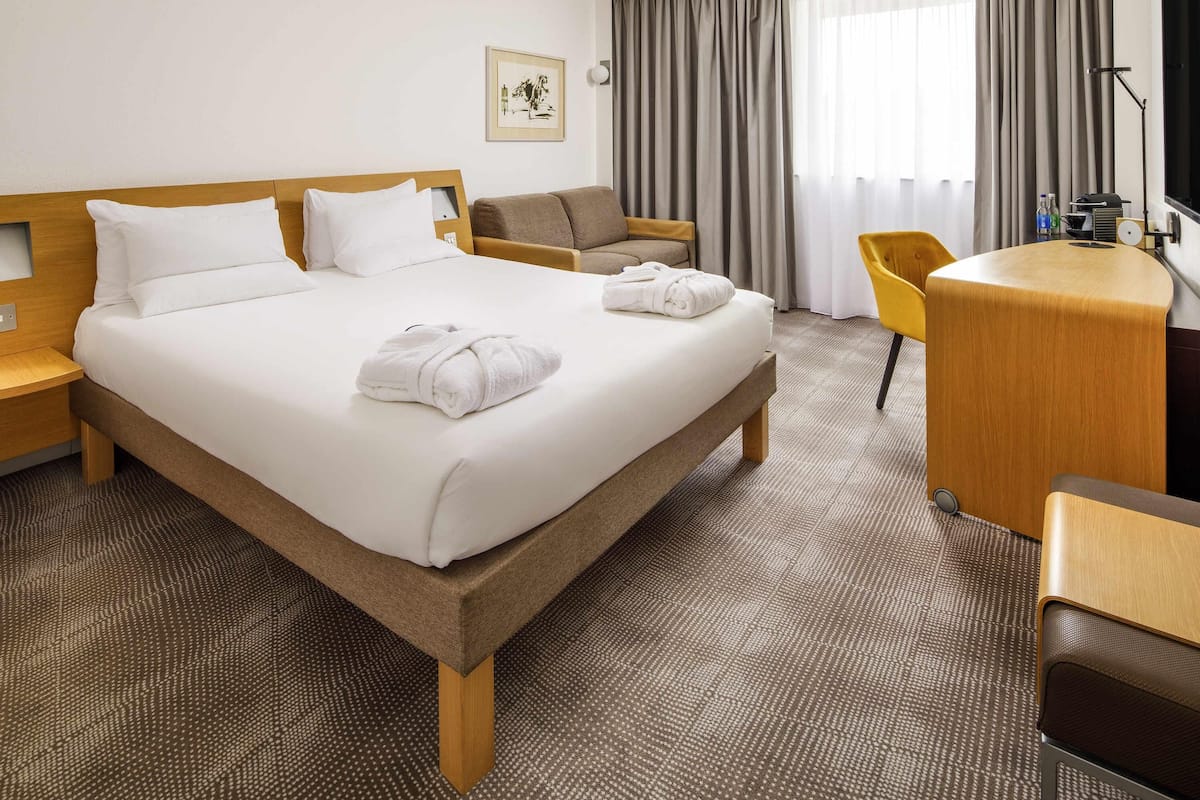 Ein Hotelzimmer mit einem Bett, einem Schreibtisch, einem Sessel und einem Fernseher.