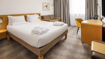 Una habitación de hotel con una cama, un escritorio, una silla y un televisor.