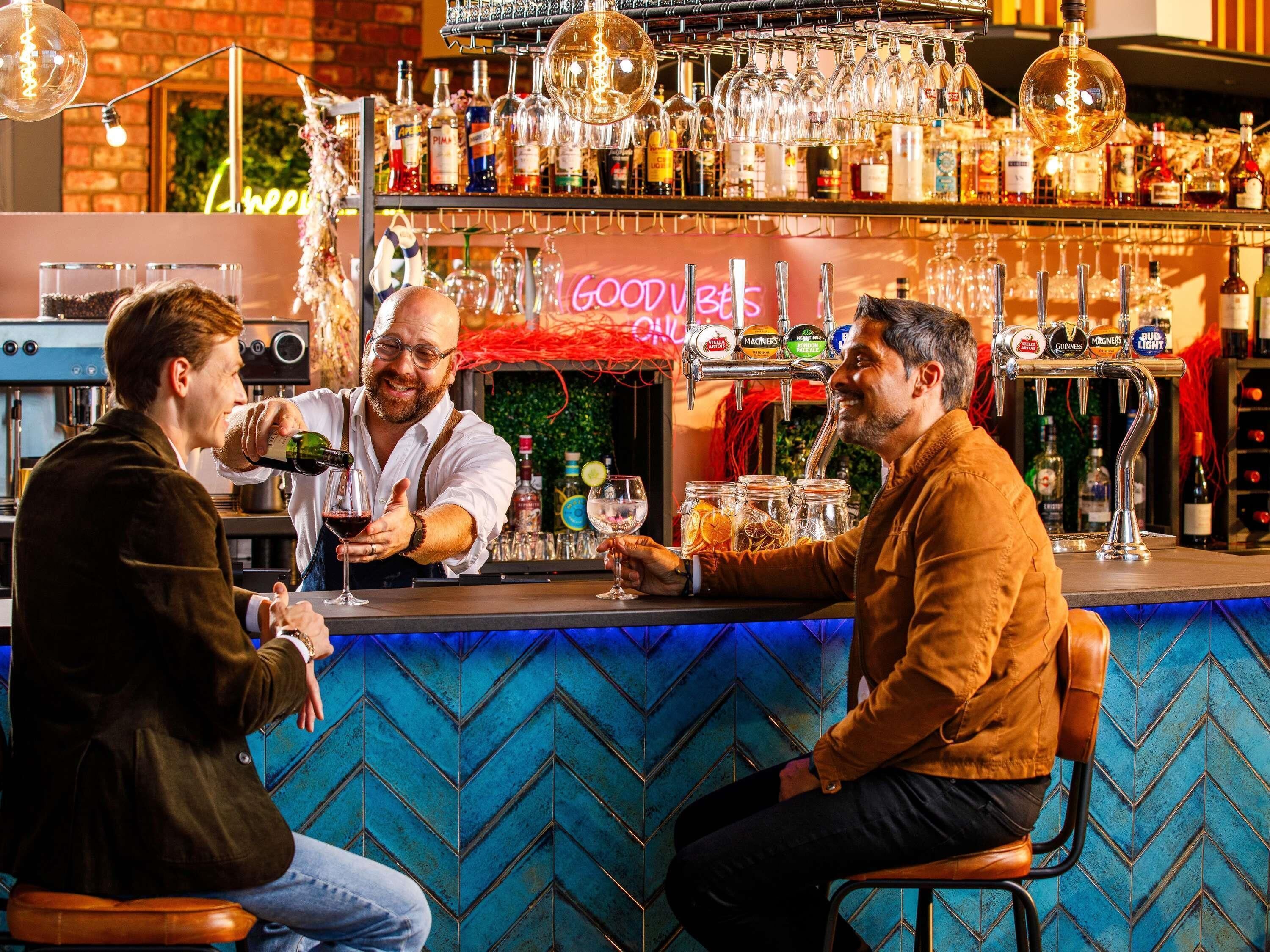 A bar area with a counter, multiple taps, and a neon sign.