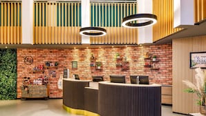 A reception area with a brick wall, wooden slats, and a reception desk. - Novotel London Greenwich (London)