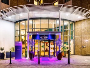 A hotel entrance with a covered walkway, a glass facade, and a sign reading 'NOVOTEL HOTELS & RESORTS.' - Novotel London Greenwich (London)