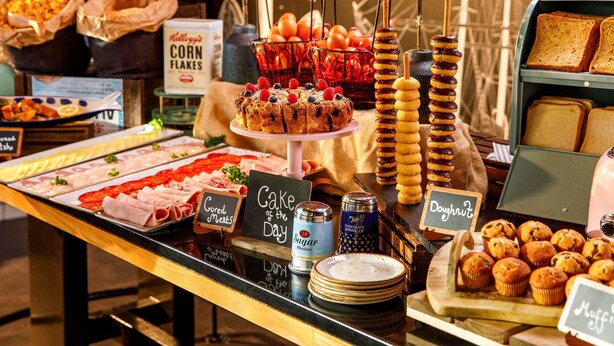 A buffet with various food items including meats, cakes, and muffins. - Novotel London Greenwich (London)
