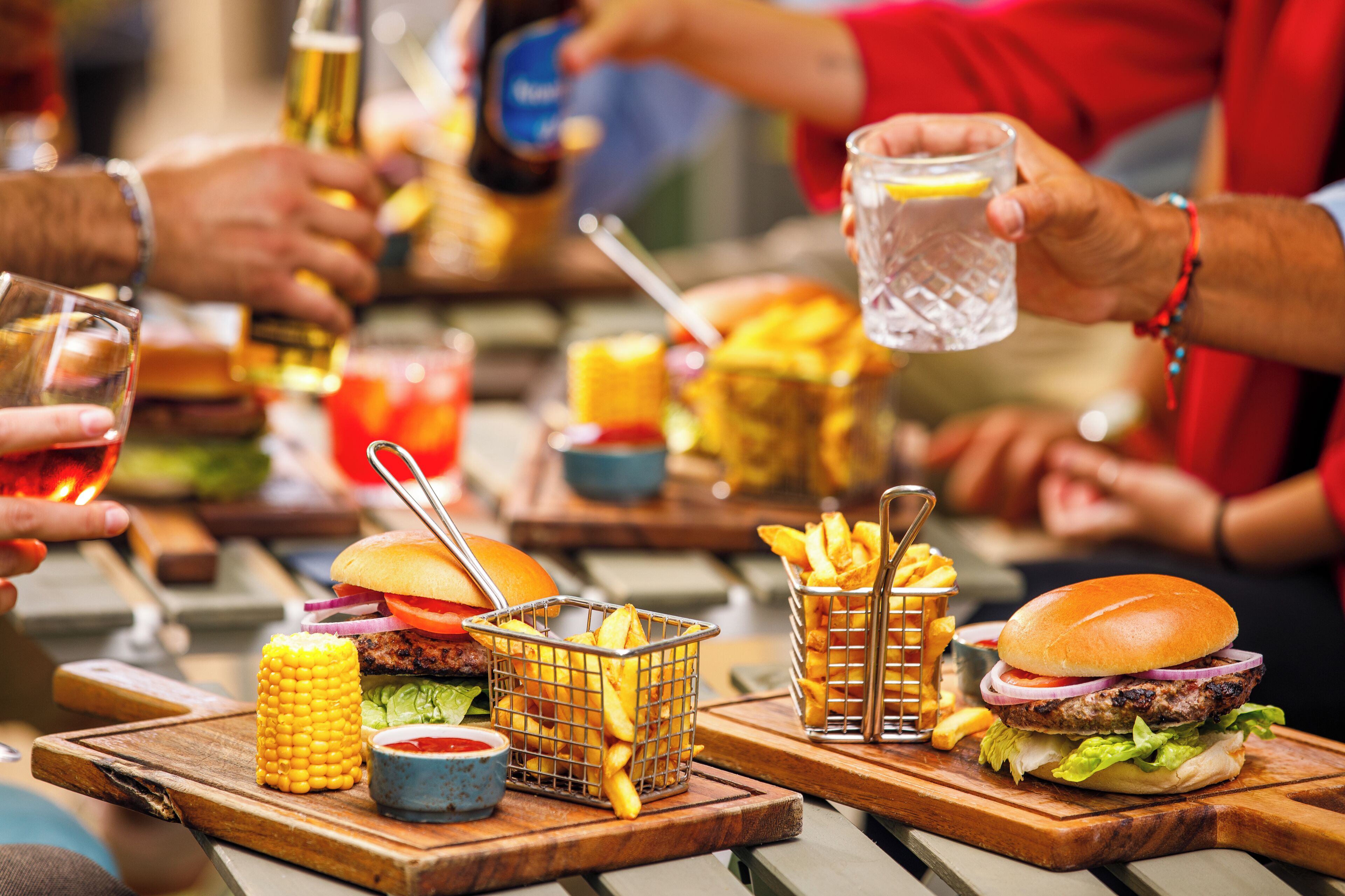 A dining table with food items including burgers, fries, and a drink.