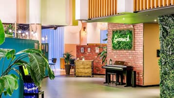 A modern lobby with a green wall, a piano, and a neon sign that reads "Greenwich".