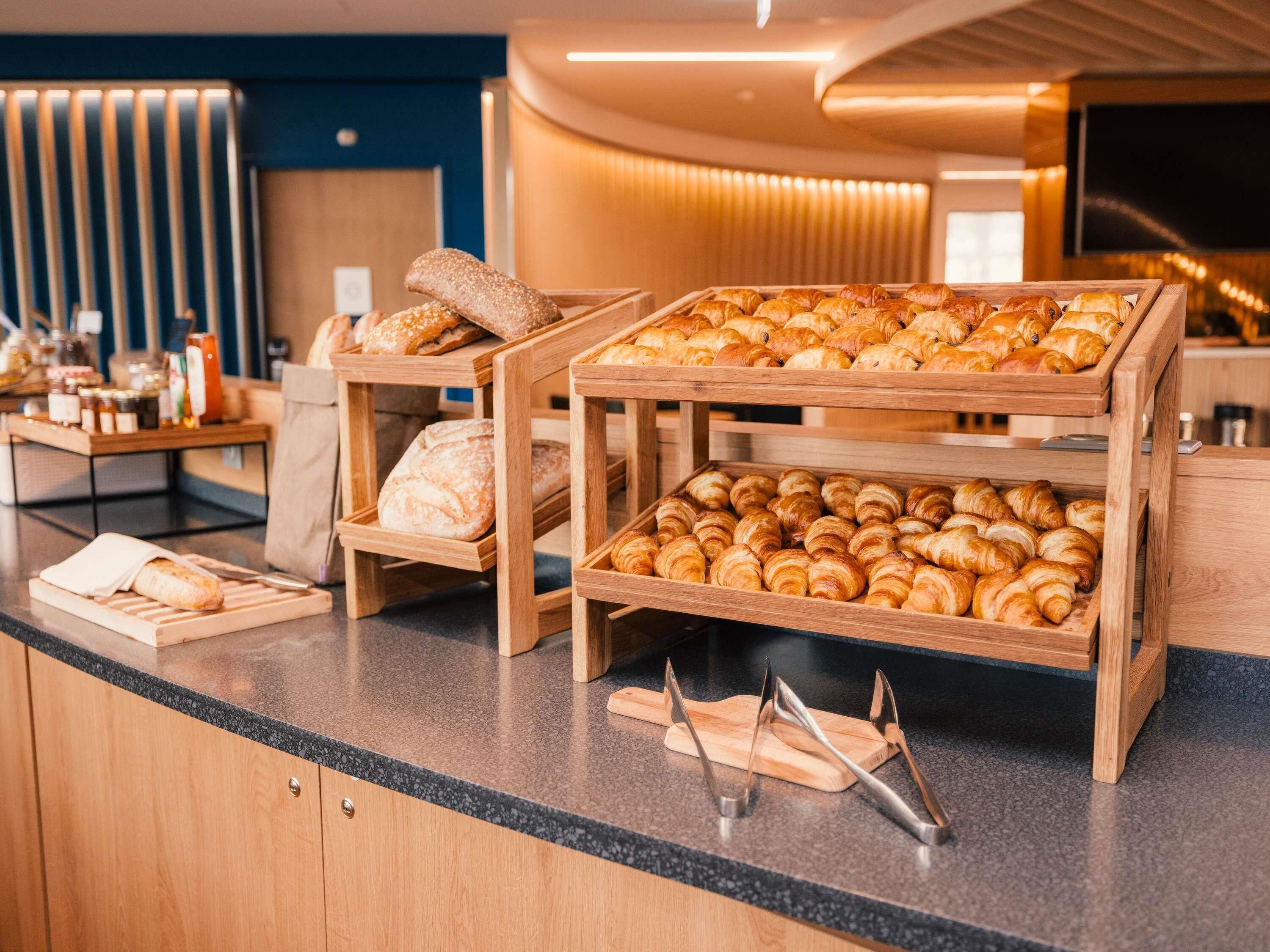 A bakery display with various breads and pastries, wooden serving boards, and a countertop with kitchen utensils.