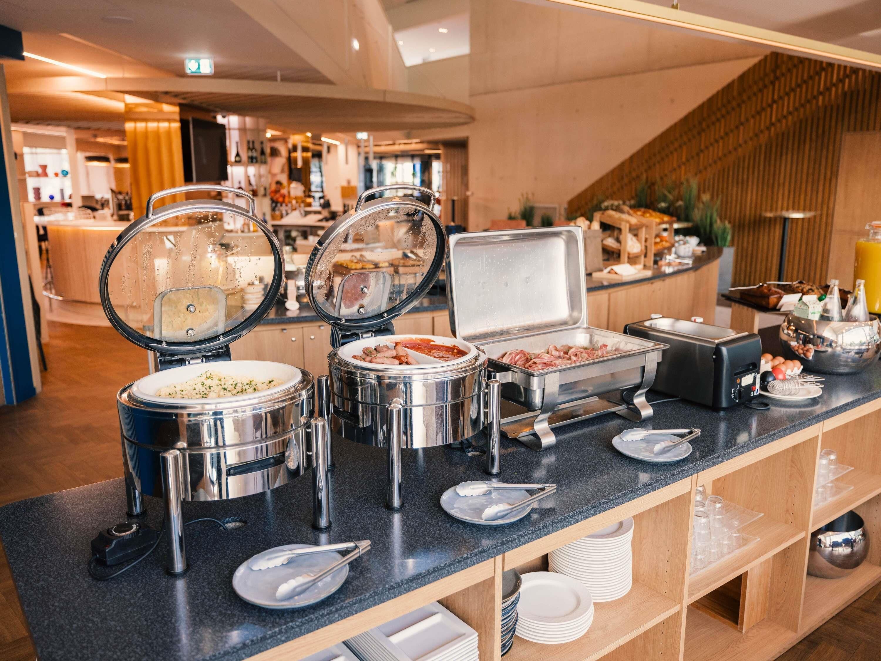 A buffet setup with various food containers and utensils on a counter.