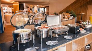 A buffet setup with various food containers and utensils on a counter.