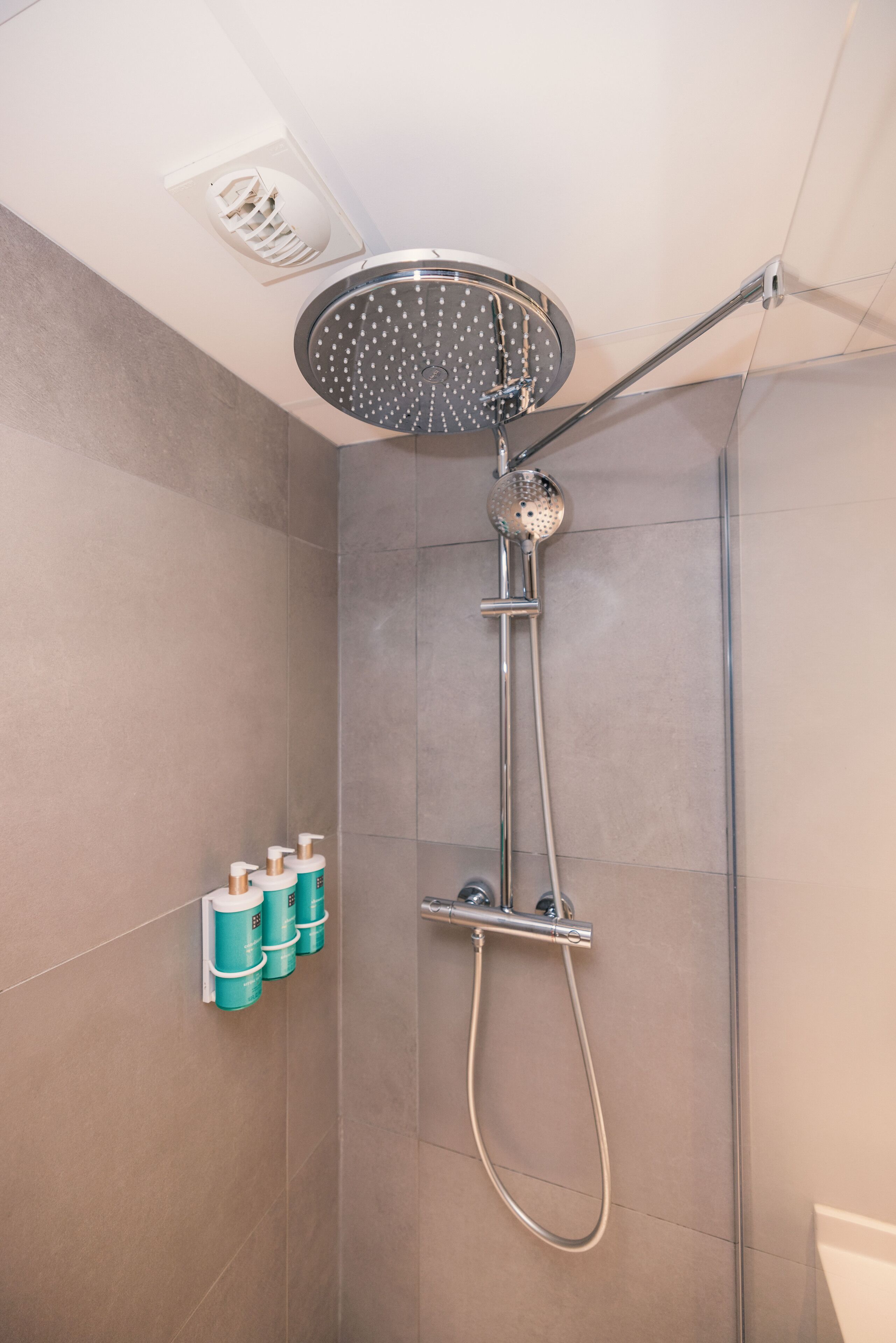 A modern shower with a handheld showerhead and a fixed overhead rain showerhead.