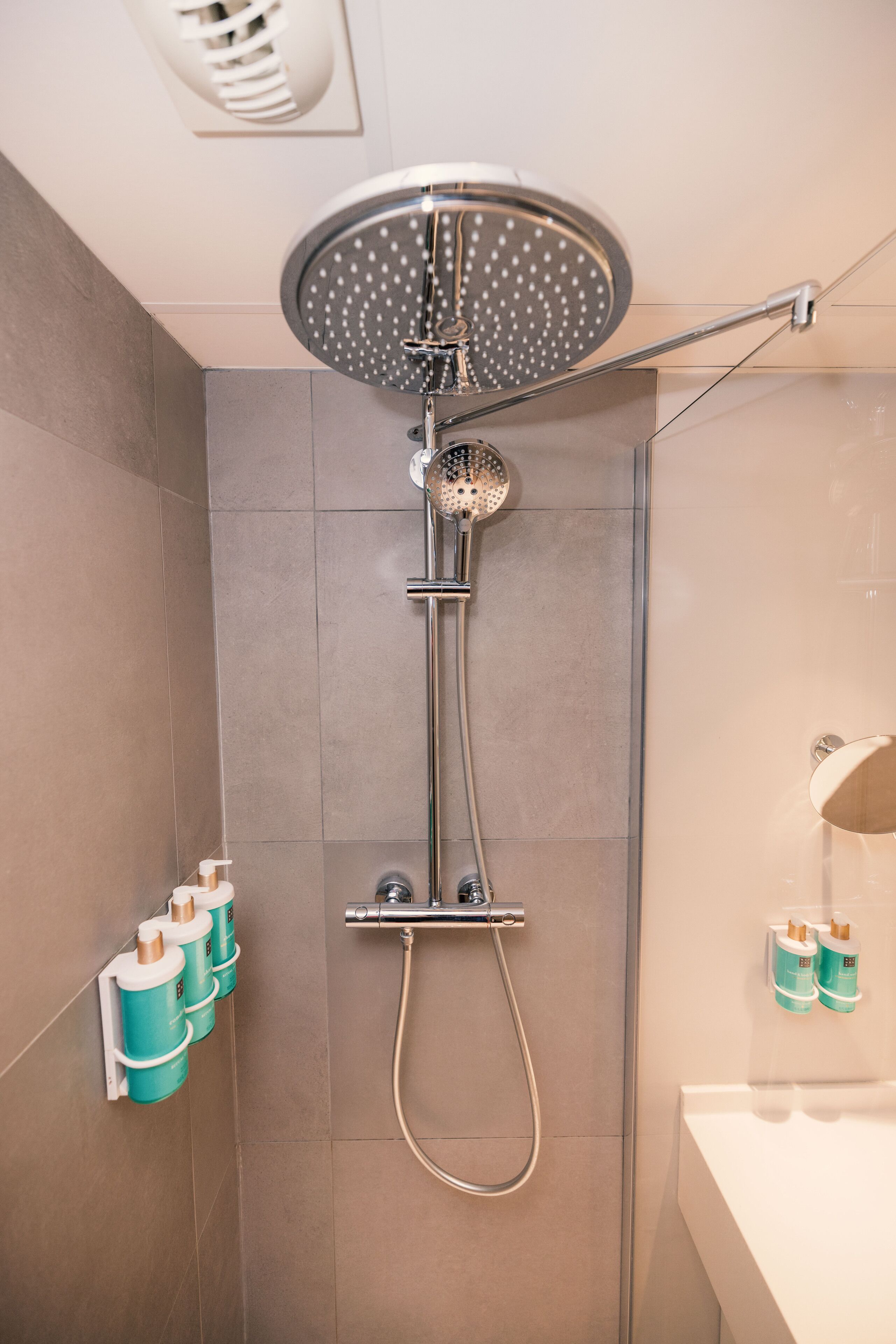 A modern shower with a rain showerhead, handheld showerhead, and a handheld faucet.