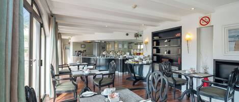 A dining area with tables set for service, a kitchen in the background, and a fireplace with a no smoking sign.