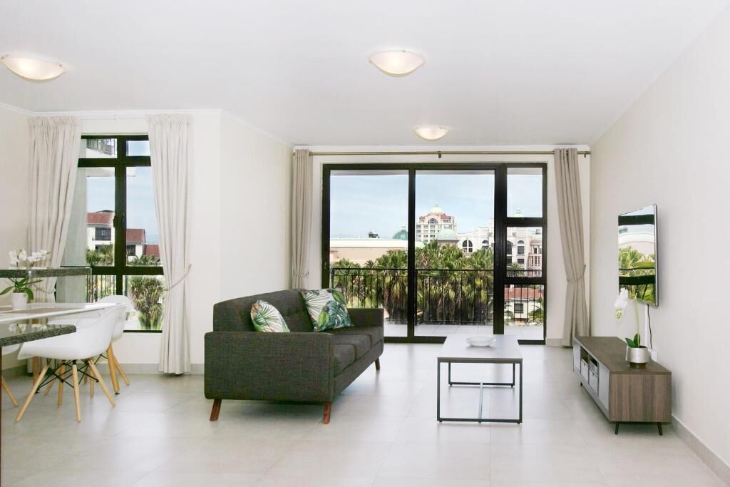 Una sala de estar moderna con sofá, mesa de comedor y televisión.