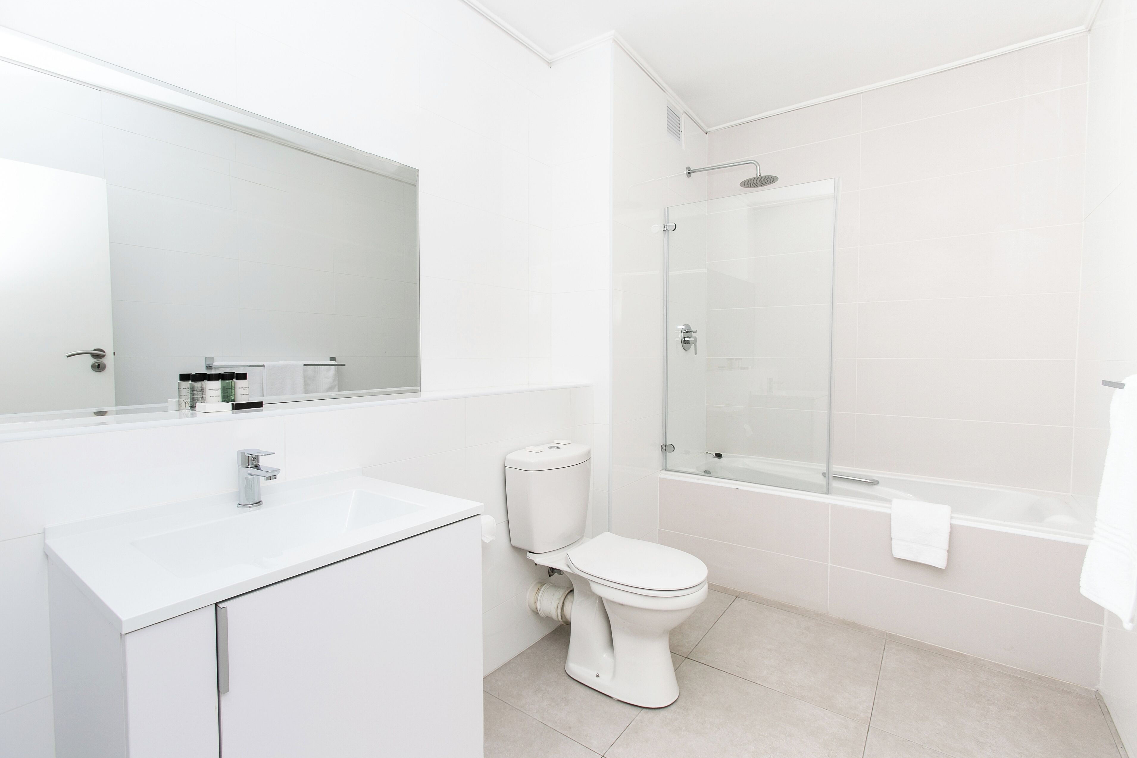 A modern bathroom with a white sink, toilet, and glass-enclosed shower.