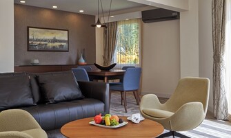 Un moderno salón con un sofá, sillas, una mesa de comedor con fruta y un cuadro en la pared.