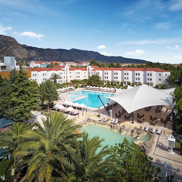 A resort with a large central pool, multiple smaller pools, and a mountain backdrop.