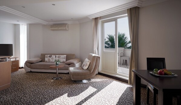 A modern living room with a sofa, armchair, and a dining table with fruit.