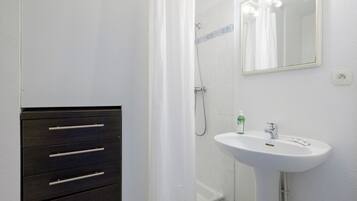 A bathroom with a white sink, a mirror, and a dark wooden cabinet with drawers.