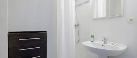 A bathroom with a white sink, a mirror, and a dark wooden cabinet with drawers.