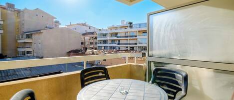 Un balcón con una mesa redonda y sillas, con vista a una zona residencial con varios edificios.