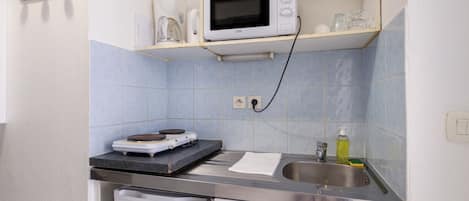 A compact kitchen with a microwave, a coffee maker, and a sink.