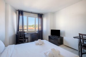 A hotel room with a bed, a desk, a chair, a TV, and a window with curtains. - ResidHotel Cannes Festival (Cannes)