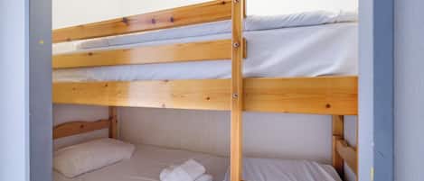 A bunk bed with white bedding and a neatly folded towel on the lower bunk.