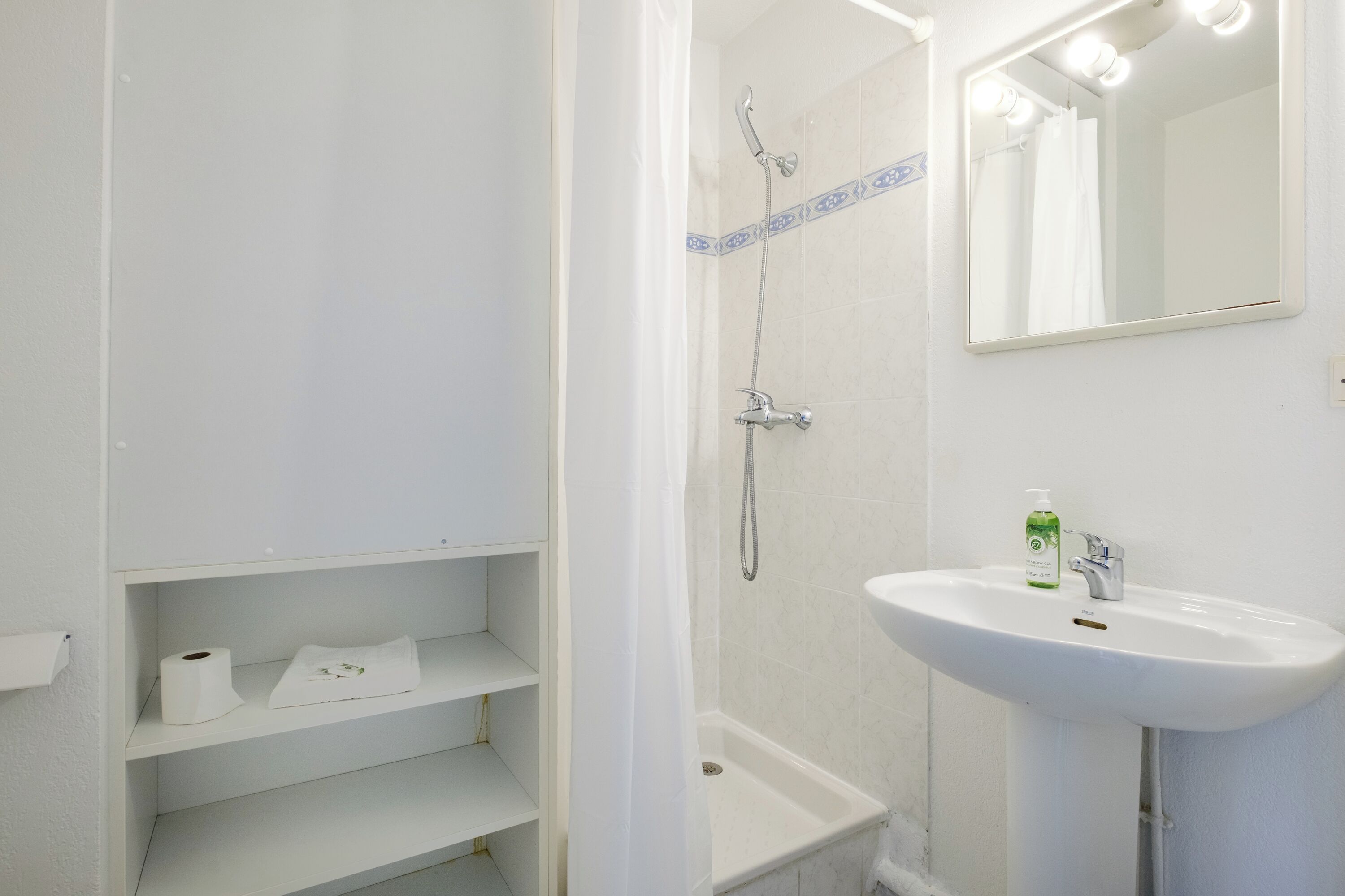 Ein Badezimmer mit Dusche, Waschbecken und Spiegel.