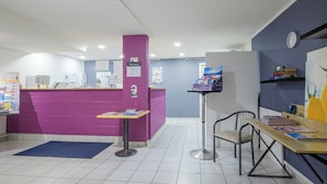 A reception area with a purple counter, a clock on the wall, and a desk with magazines.