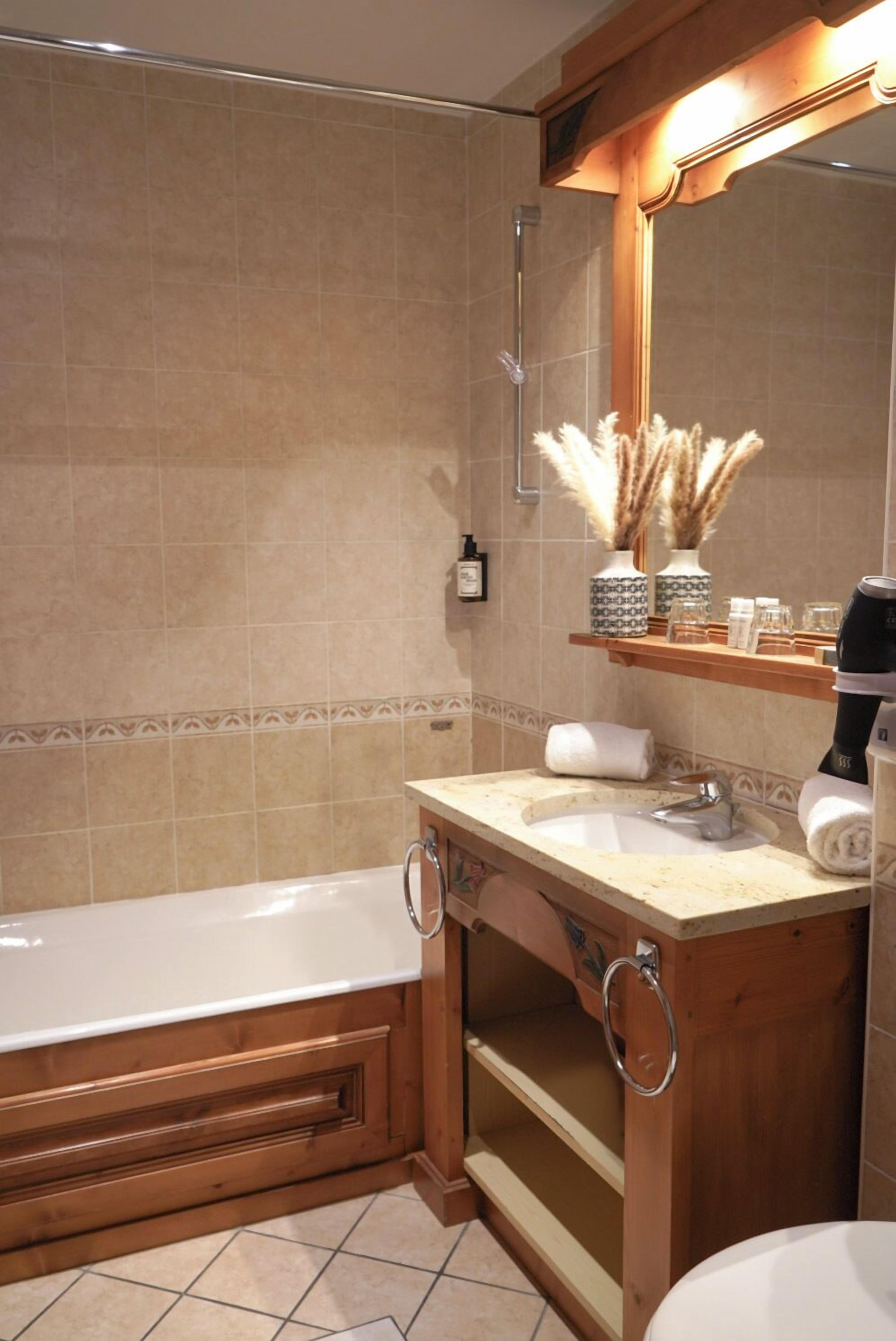 A bathroom with a bathtub, a sink, a mirror, and a shelf with toiletries.
