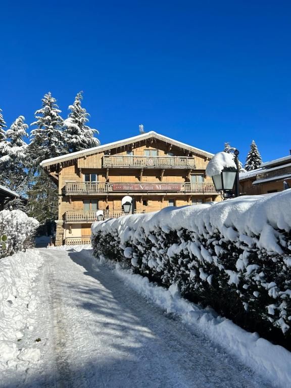 A snow-covered path leading to a building with a balcony and a sign that reads 'Hotel Vigor.'