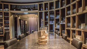 Ein langer, glänzender Tisch in einer modernen Bar, an den Wänden Holzregale mit Flaschen und Gläsern.