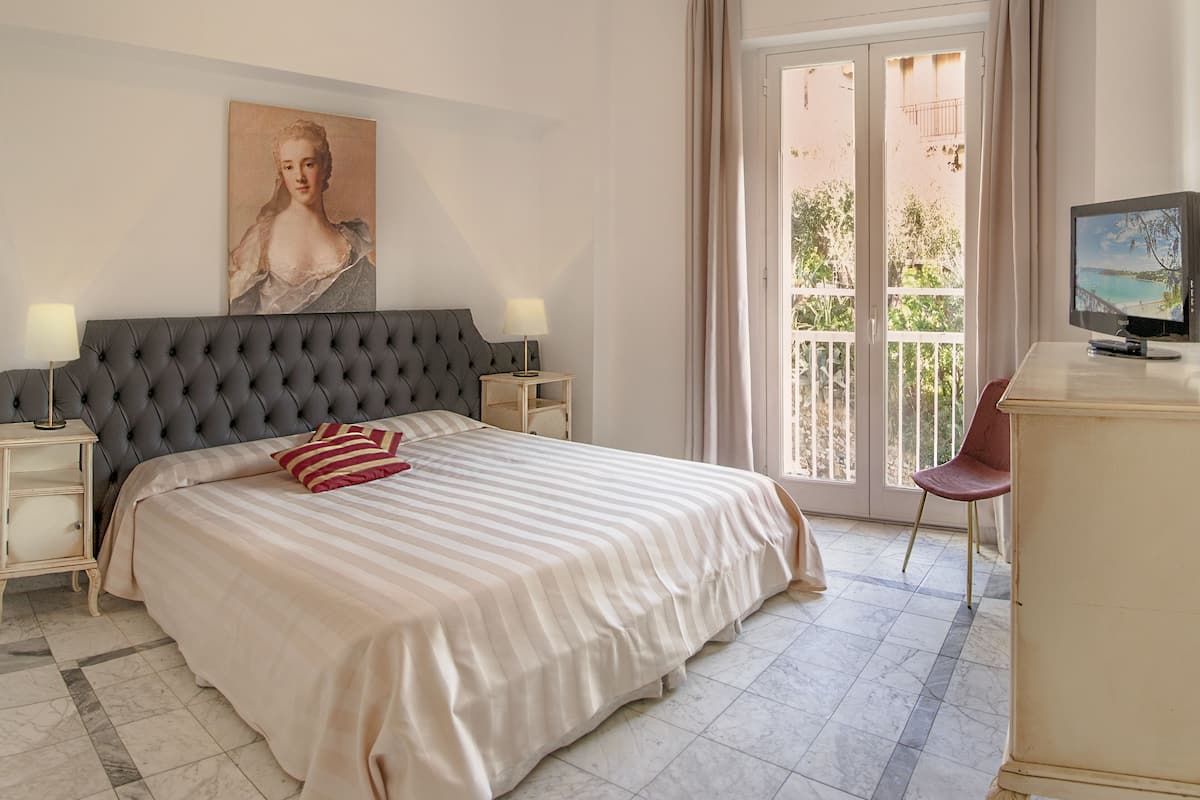 Una camera da letto con un letto grande, un comodino, una TV e un balcone con vista.