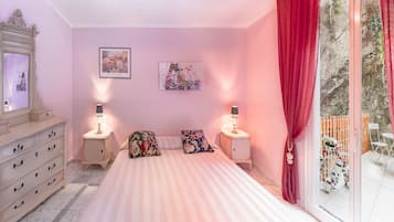 Un dormitorio con cama, cómoda, dos mesitas de noche con lámparas y una ventana con cortinas.