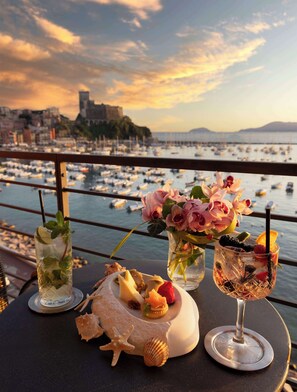 A table with drinks and snacks, overlooking a marina with boats and a cityscape in the background. - Hotel Shelley e delle Palme, BW Signature Collection (Lerici)