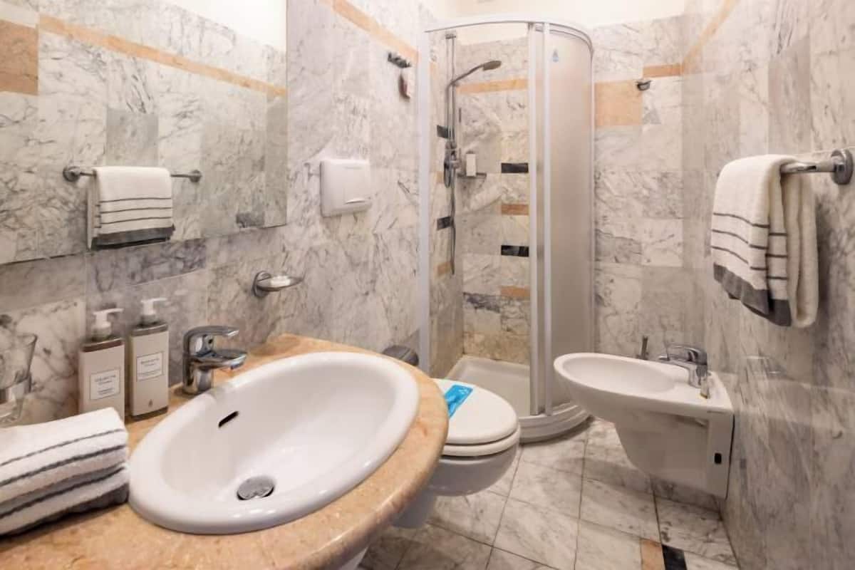 Un bagno con lavandino, wc, bidet e doccia con pareti in vetro.