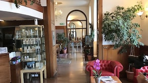 Een ruime lobby met een rode leren bank, een salontafel en een glazen vitrine.