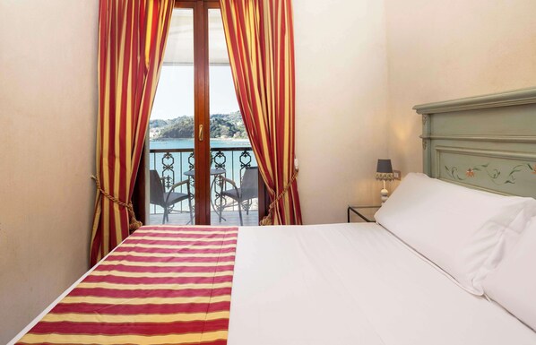 A hotel room with a bed, a view of a balcony with chairs, and a table. - Hotel Shelley e delle Palme, BW Signature Collection (Lerici)