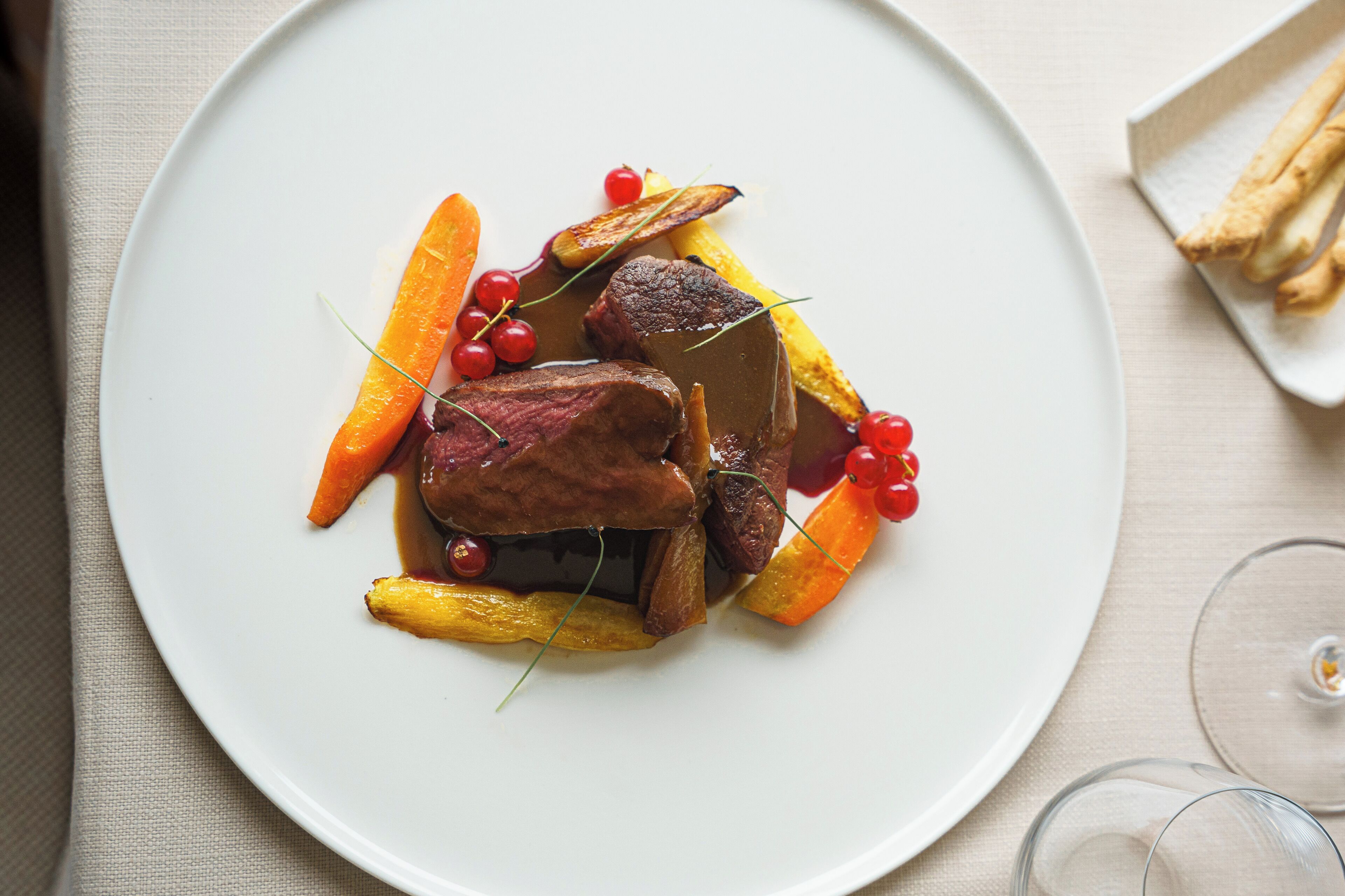 Un piatto con carne, verdure e frutti di bosco.