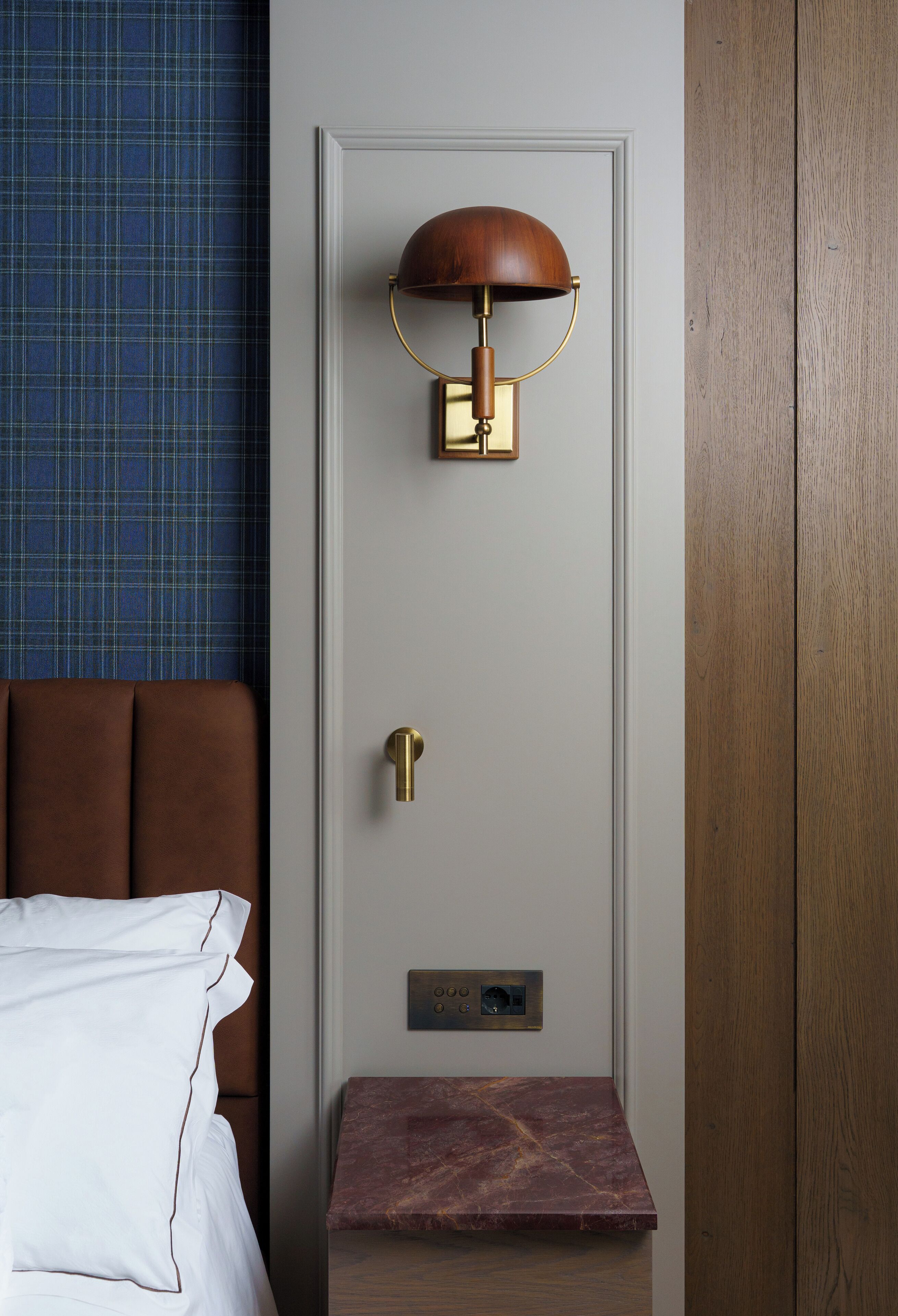 A hotel room with a bed, a nightstand, a lamp, and a door.