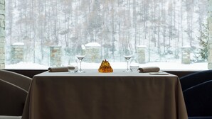 Een tafel voor twee met zicht op een besneeuwd bos door een raam.