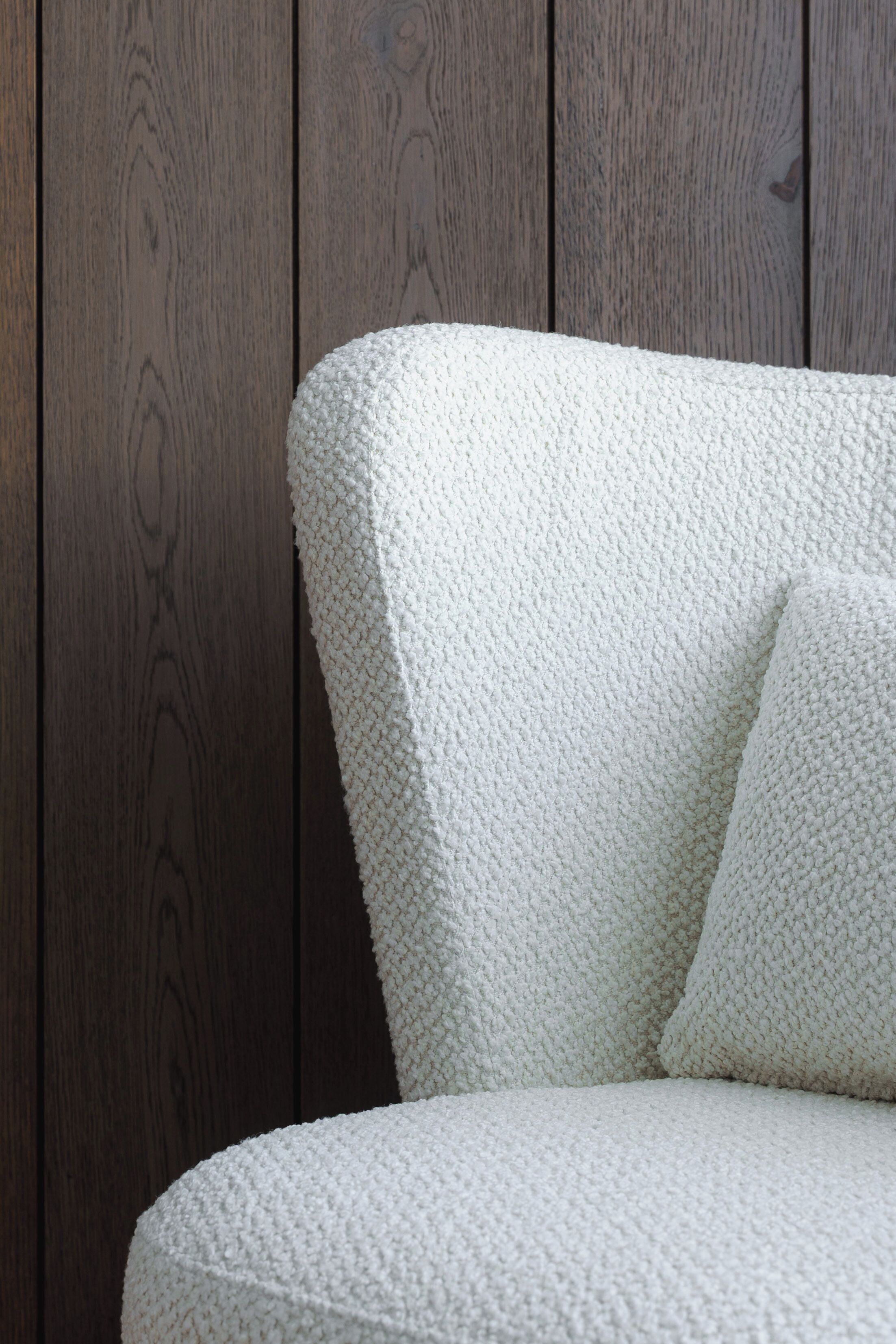 Un sofá blanco con textura frente a una pared de madera.